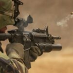 Close-up of a soldier in camo firing a rifle in action during training.